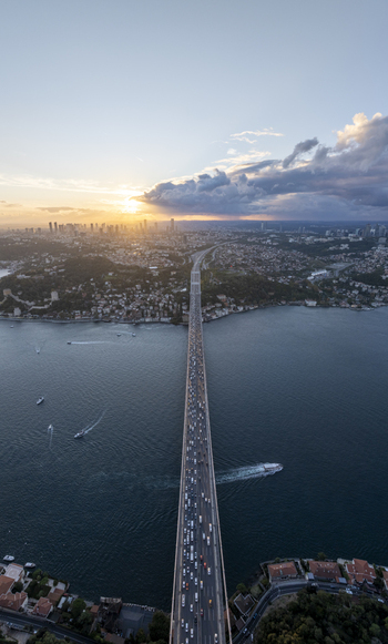Aerial view of Fatih Sultan Mehmet Bridge spanning the Bosphorus with heavy traffic at sunset surrounded by the city skyline and calm waters in Beykoz Istanbul Turkey. Aerial view of Fatih Sultan Mehmet Bridge spanning the Bosphorus with heavy traffic at sunset surrounded by the city skyline and calm waters in Beykoz Istanbul Turkey.