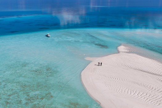 Aerial view of lush tropical islands with green palm trees and turquoise coral reefs surrounded by the deep blue ocean under a clear sky near Vaanee Dhaalu Atoll Maldives. Aerial view of lush tropical islands with green palm trees and turquoise coral reefs surrounded by the deep blue ocean under a clear sky near Vaanee Dhaalu Atoll Maldives.