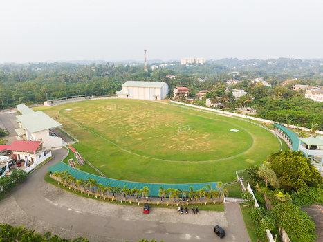 Aerial view of a green sports field with an oval track surrounded by lush tropical trees and urban buildings in Galle Southern Province Sri Lanka.