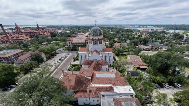 Aerial view of Memorial Presbyterian Church with its distinctive dome and red tile roofs surrounded by historic buildings and lush greenery in St. Augustine Florida United States.