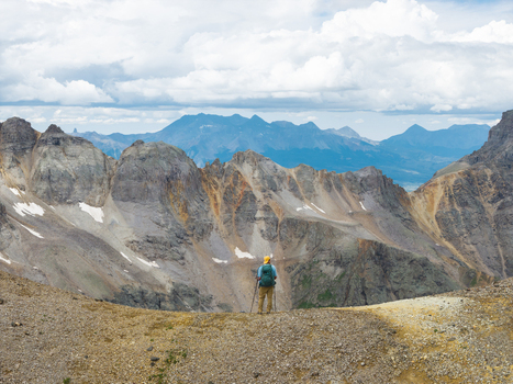 Aerial view of a hiker standing on a rocky ridge overlooking the dramatic peaks of the San Juan Mountain Range near Mount Sneffels in Ouray Colorado United States. Aerial view of a hiker standing on a rocky ridge overlooking the dramatic peaks of the San Juan Mountain Range near Mount Sneffels in Ouray Colorado United States.