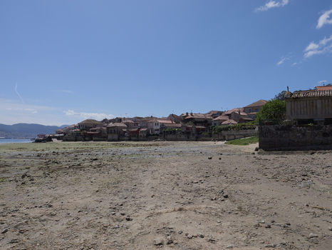 View of the historic coastal village of Combarro with traditional stone granaries lining the waterfront and rocky beach at low tide in Combarro Pontevedra Spain.