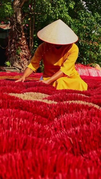View of a person working among red incense sticks Vietnam.