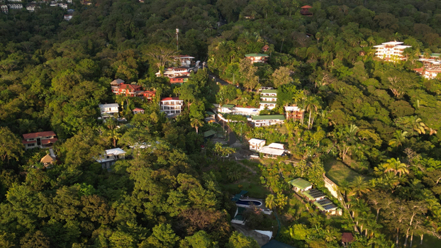 Aerial view of vibrant homes nestled amidst the dense verdant rainforest canopy a striking contrast of human construction and natural splendor Quepos Puntarenas Province Costa Rica.