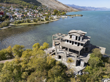 Aerial view of an abandoned concrete structure on the shore of Lake Shkodra surrounded by trees and overlooking the town of Shiroka Shkoder County Albania. Aerial view of an abandoned concrete structure on the shore of Lake Shkodra surrounded by trees and overlooking the town of Shiroka Shkoder County Albania.