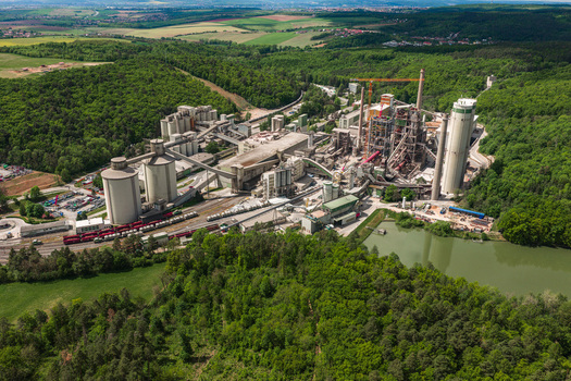 Aerial view of a large cement plant industrial complex surrounded by dense green forests and rolling hills in Mokra Horakov Jihomoravsky kraj Czechia. Aerial view of a large cement plant industrial complex surrounded by dense green forests and rolling hills in Mokra Horakov Jihomoravsky kraj Czechia.