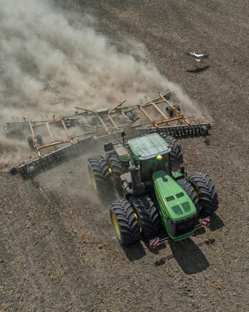 Aerial view of a green tractor with yellow wheels kicking up dust as it tills the brown earth Chyhyryns kyi district Cherkasy Oblast Ukraine. Aerial view of a green tractor with yellow wheels kicking up dust as it tills the brown earth Chyhyryns kyi district Cherkasy Oblast Ukraine.