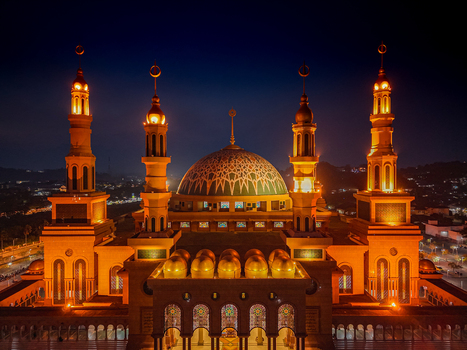 Aerial view of the Baitul Muttaqien Mosque illuminated at night with its prominent dome and minarets in Samarinda East Kalimantan Indonesia.