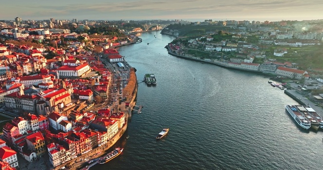 Aerial view of the Douro River flowing through the historic city of Porto with traditional red tiled rooftops and boats in Porto Portugal. Aerial view of the Douro River flowing through the historic city of Porto with traditional red tiled rooftops and boats in Porto Portugal.