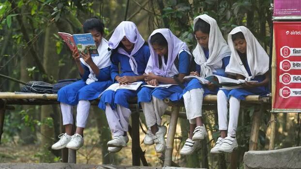 View of schoolgirls in blue uniforms reading books Bangladesh.