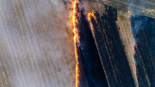 Aerial view of a field fire burning dry stubble with thick smoke and charred earth in Sremska Mitrovica Vojvodina Serbia. Aerial view of a field fire burning dry stubble with thick smoke and charred earth in Sremska Mitrovica Vojvodina Serbia.