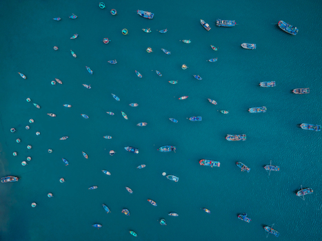 Aerial view of numerous small fishing boats scattered across the deep blue water in Vietnam. Aerial view of numerous small fishing boats scattered across the deep blue water in Vietnam.