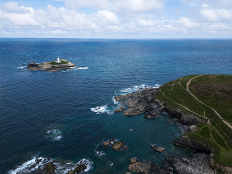 Aerial view of Godrevy Lighthouse on a rocky island off the coast of Godrevy Beach with rugged cliffs and turquoise water in Gwithian England United Kingdom. Aerial view of Godrevy Lighthouse on a rocky island off the coast of Godrevy Beach with rugged cliffs and turquoise water in Gwithian England United Kingdom.