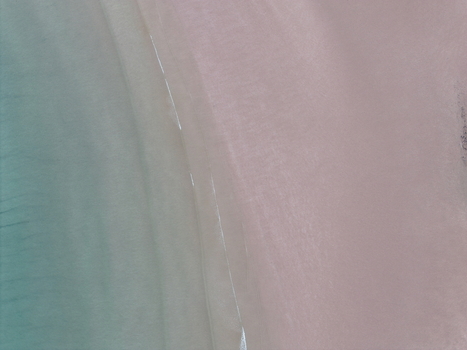 Aerial view of the turquoise waters and pink sand of Gruinard Bay with gentle waves washing over the shoreline in Gruinard Scotland United Kingdom. Aerial view of the turquoise waters and pink sand of Gruinard Bay with gentle waves washing over the shoreline in Gruinard Scotland United Kingdom.