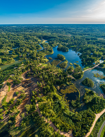 Aerial view of a lush green landscape featuring winding lakes dense forests and dirt roads Latvia. Aerial view of a lush green landscape featuring winding lakes dense forests and dirt roads Latvia.