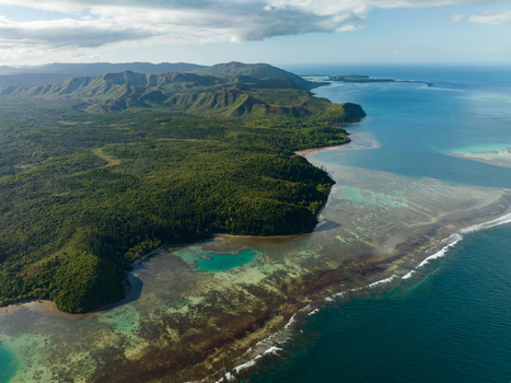 Aerial view of the vibrant coastline where lush green forests meet the turquoise sea contrasting against the rugged mountain backdrop Goro South Province New Caledonia. Aerial view of the vibrant coastline where lush green forests meet the turquoise sea contrasting against the rugged mountain backdrop Goro South Province New Caledonia.