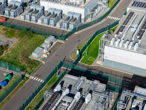 Aerial view of a data center with industrial cooling units secure fencing and paved access roads in the United Kingdom.
