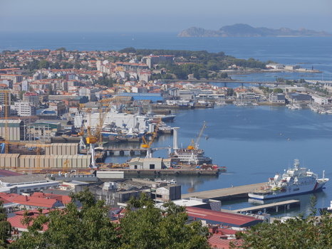 View of the industrial port of Vigo with large cranes cargo ships and urban buildings along the coastline in Vigo Pontevedra Spain.