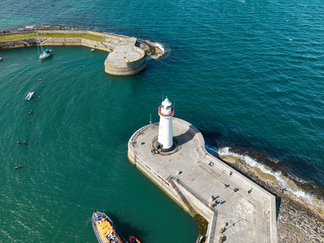 Aerial view of Donaghadee Harbour featuring its iconic white lighthouse stone pier turquoise sea and small boats in Donaghadee Northern Ireland United Kingdom. Aerial view of Donaghadee Harbour featuring its iconic white lighthouse stone pier turquoise sea and small boats in Donaghadee Northern Ireland United Kingdom.