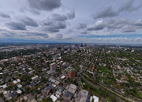 Aerial view of the Cherry Creek neighborhood featuring dense residential housing lush tree lined streets and the distant downtown Denver skyline under a cloudy sky in Denver Colorado United States. Aerial view of the Cherry Creek neighborhood featuring dense residential housing lush tree lined streets and the distant downtown Denver skyline under a cloudy sky in Denver Colorado United States.
