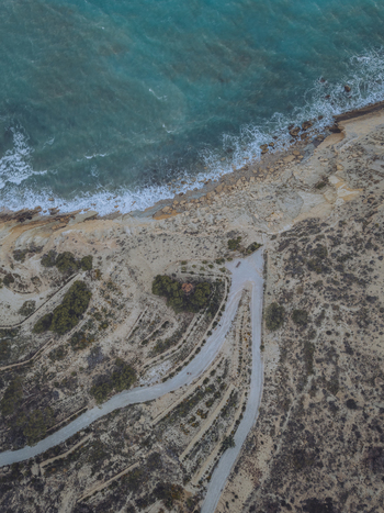 Aerial view of Santuari iber i roma de la Malladeta on a rocky cliff overlooking the turquoise Mediterranean Sea with winding paths and coastal vegetation La Vila Joiosa Comunidad Valenciana Spain. Aerial view of Santuari iber i roma de la Malladeta on a rocky cliff overlooking the turquoise Mediterranean Sea with winding paths and coastal vegetation La Vila Joiosa Comunidad Valenciana Spain.