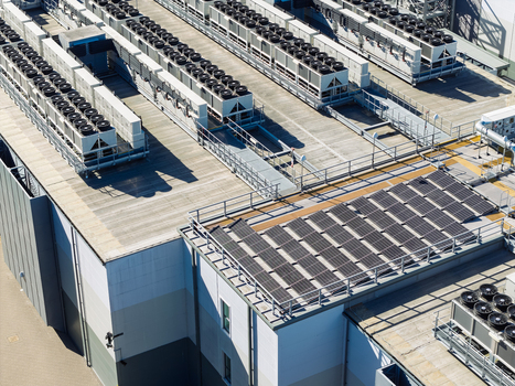 Aerial view of a data center roof featuring rows of industrial HVAC cooling units and solar panels in the United Kingdom.