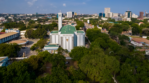 Aerial view of the Holy Spirit Cathedral surrounded by lush green trees and urban buildings under a clear blue sky in Accra Greater Accra Region Ghana. Aerial view of the Holy Spirit Cathedral surrounded by lush green trees and urban buildings under a clear blue sky in Accra Greater Accra Region Ghana.