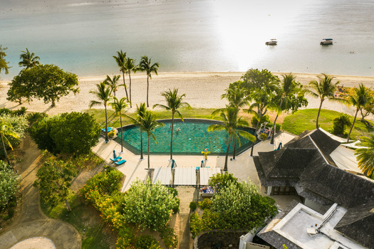 Aerial view of a luxury resort featuring a turquoise swimming pool surrounded by palm trees and a white sand beach in Moka District Mauritius. Aerial view of a luxury resort featuring a turquoise swimming pool surrounded by palm trees and a white sand beach in Moka District Mauritius.