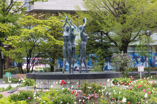 View of the Three Maidens bronze statue surrounded by colorful blooming tulips in Odori Park in Sapporo Hokkaido Japan. View of the Three Maidens bronze statue surrounded by colorful blooming tulips in Odori Park in Sapporo Hokkaido Japan.