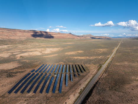 Aerial view of a solar farm with rows of photovoltaic panels situated in an arid desert landscape next to a highway with red rock mesas in Colorado United States. Aerial view of a solar farm with rows of photovoltaic panels situated in an arid desert landscape next to a highway with red rock mesas in Colorado United States.