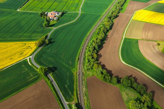 Aerial view of vibrant agricultural fields with yellow rapeseed green crops and a railway line passing through the countryside near Hofgeismar Hessen Germany. Aerial view of vibrant agricultural fields with yellow rapeseed green crops and a railway line passing through the countryside near Hofgeismar Hessen Germany.