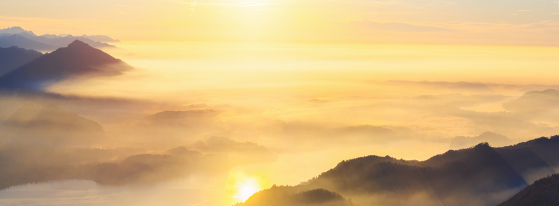 Aerial view of Mottarone mountain range at sunrise with golden light illuminating the peaks and thick fog filling the valleys below in Mottarone Piedmont Italy. Aerial view of Mottarone mountain range at sunrise with golden light illuminating the peaks and thick fog filling the valleys below in Mottarone Piedmont Italy.
