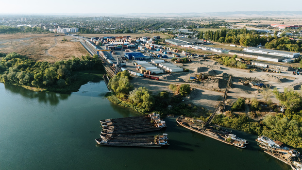 Sremska Mitrovica Serbia 16 September 2026 Aerial view of the industrial port area on the Sava River with cargo barges shipping containers and gravel piles. Sremska Mitrovica Serbia 16 September 2026 Aerial view of the industrial port area on the Sava River with cargo barges shipping containers and gravel piles.