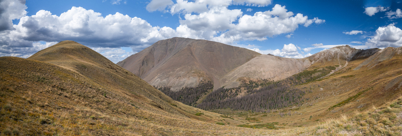 View of the rugged slopes of San Luis Peak and the surrounding alpine landscape with dry grasses and pine forests under a blue sky in Creede Colorado United States. View of the rugged slopes of San Luis Peak and the surrounding alpine landscape with dry grasses and pine forests under a blue sky in Creede Colorado United States.