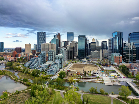 Aerial view of the Calgary skyline featuring modern skyscrapers the Bow River and urban parkland under a cloudy sky in Calgary Alberta Canada.