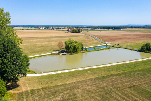 Aerial view of the Open Beatz Festival site featuring a calm pond lush green trees and vast agricultural fields in Herzogenaurach Bayern Germany. Aerial view of the Open Beatz Festival site featuring a calm pond lush green trees and vast agricultural fields in Herzogenaurach Bayern Germany.