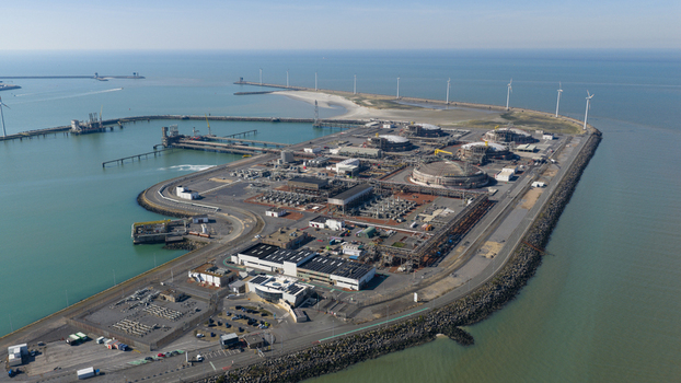 Aerial view of Fluxys LNG Terminal Zeebrugge featuring large storage tanks industrial infrastructure and wind turbines along the coast in Brugge Vlaanderen Belgium. Aerial view of Fluxys LNG Terminal Zeebrugge featuring large storage tanks industrial infrastructure and wind turbines along the coast in Brugge Vlaanderen Belgium.