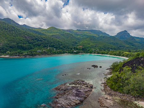 Aerial view of turquoise waters meet lush green hills along the shores of Port Launay Mahe Island Seychelles. Aerial view of turquoise waters meet lush green hills along the shores of Port Launay Mahe Island Seychelles.