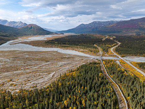 Aerial view of the Delta River winding through boreal forest and mountains with the Trans Alaska Pipeline running alongside the highway in Southeast Fairbanks Alaska United States. Aerial view of the Delta River winding through boreal forest and mountains with the Trans Alaska Pipeline running alongside the highway in Southeast Fairbanks Alaska United States.