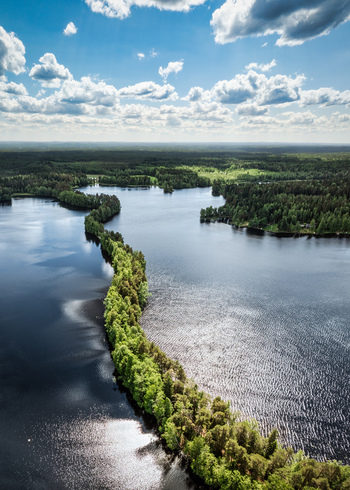 Aerial view of Liesjarvi National Park featuring a narrow forested ridge separating two lakes under a bright blue sky with clouds in Tammela Finland. Aerial view of Liesjarvi National Park featuring a narrow forested ridge separating two lakes under a bright blue sky with clouds in Tammela Finland.