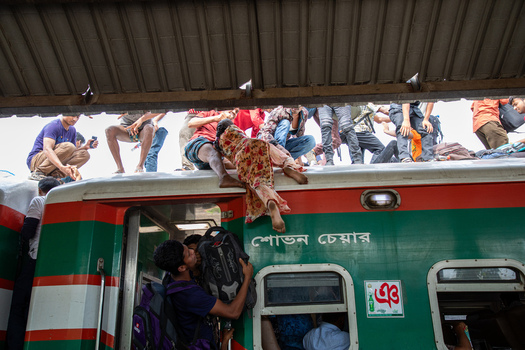 Dhaka Bangladesh 14 June 2018 View of people climbing onto the roof of a crowded train at Airport Railway Station during the Eid al Fitr holiday rush. Dhaka Bangladesh 14 June 2018 View of people climbing onto the roof of a crowded train at Airport Railway Station during the Eid al Fitr holiday rush.