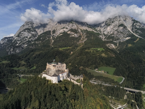 Aerial view of Burg Hohenwerfen perched on a rocky outcrop surrounded by lush green forests and the dramatic peaks of the Alps in Werfen Salzburg Austria. Aerial view of Burg Hohenwerfen perched on a rocky outcrop surrounded by lush green forests and the dramatic peaks of the Alps in Werfen Salzburg Austria.