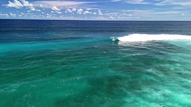 Aerial view of a surfer riding a wave in Indonesia.