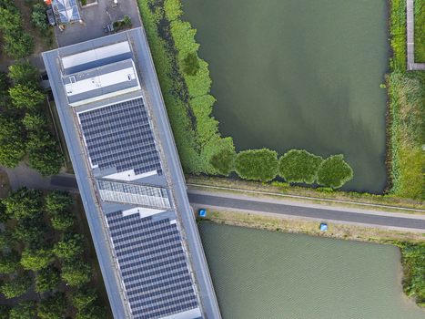 Aerial view of High Tech Campus Eindhoven featuring a building with rooftop solar panels adjacent to a canal and lush green trees in Eindhoven Noord Brabant Netherlands. Aerial view of High Tech Campus Eindhoven featuring a building with rooftop solar panels adjacent to a canal and lush green trees in Eindhoven Noord Brabant Netherlands.
