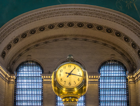 View of the iconic four faced opal clock in the Main Concourse of Grand Central Terminal with the ornate zodiac ceiling and arched windows New York New York United States. View of the iconic four faced opal clock in the Main Concourse of Grand Central Terminal with the ornate zodiac ceiling and arched windows New York New York United States.