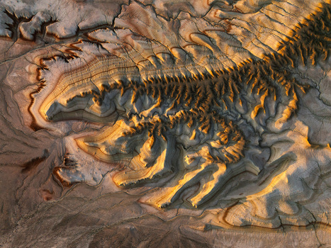 Aerial view of textured canyons and layered plateaus bathed in the warm glow of the setting sun creating a stark contrast with the shadows Almaty Kazakhstan.