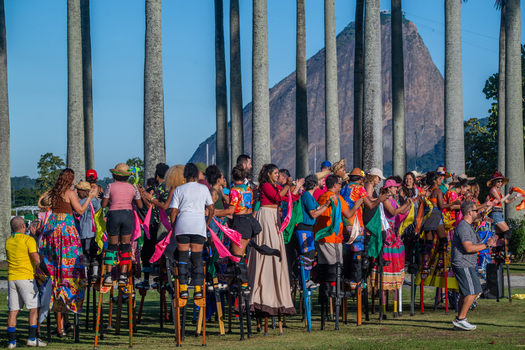 Rio de Janeiro Brazil 20 June 2026 View of Festa Junina performers on stilts wearing colorful traditional costumes with palm trees and Sugarloaf Mountain in the background. Rio de Janeiro Brazil 20 June 2026 View of Festa Junina performers on stilts wearing colorful traditional costumes with palm trees and Sugarloaf Mountain in the background.