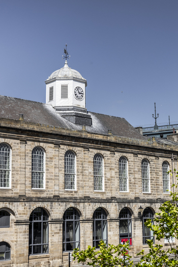 View of the historic Guildhall building with its prominent clock tower and arched windows under a clear blue sky in Newcastle upon Tyne England United Kingdom. View of the historic Guildhall building with its prominent clock tower and arched windows under a clear blue sky in Newcastle upon Tyne England United Kingdom.