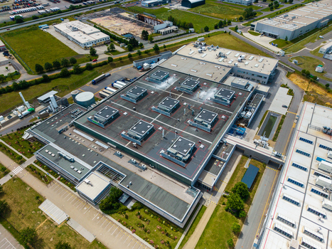 Aerial view of a large industrial facility with flat roofs multiple HVAC units surrounding parking areas and green spaces in Zebrak Central Bohemian Region Czechia. Aerial view of a large industrial facility with flat roofs multiple HVAC units surrounding parking areas and green spaces in Zebrak Central Bohemian Region Czechia.