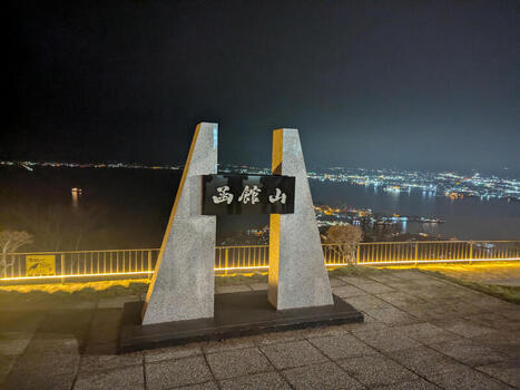 View of the Mount Hakodate sign illuminated at night with the glowing city lights of Hakodate in the background Hakodate Hokkaido Japan.